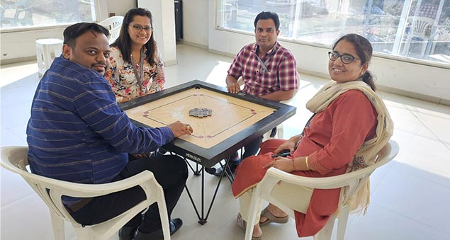 team members playing competitive indoor carrom tournament in 2022