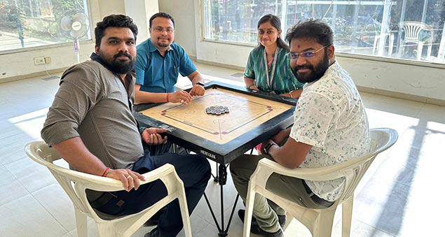 team members playing competitive indoor carrom tournament in 2022