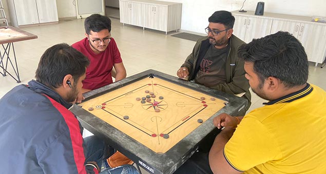 team members playing competitive indoor carrom tournament in 2022